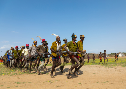 Men running in line with weapons during the proud ox ceremony in the Dassanech tribe, Turkana County, Omorate, Ethiopia