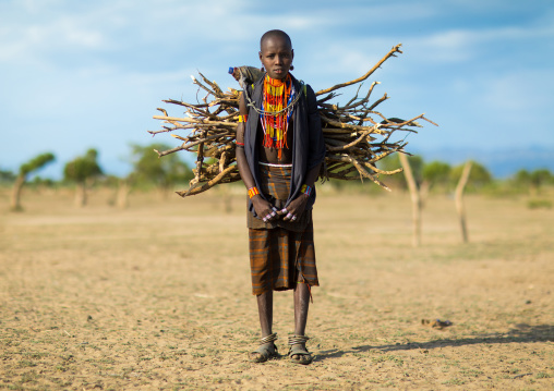 Erbore tribe girl carrying some wood on her back, Omo valley, Murale, Ethiopia