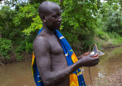 Bodi tribe man cleaning his shield before the Kael ceremony, Omo valley, Hana Mursi, Ethiopia