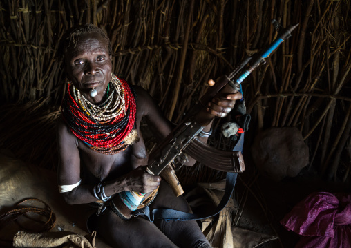 Nyangatom tribe woman holding a kalashnikov in her hut, Omo valley, Kangate, Ethiopia