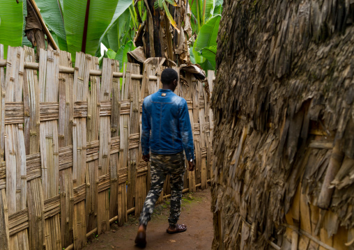 Man passing along a traditional dorze house made of bamboo and enset leaves, Gamo Gofa Zone, Gamole, Ethiopia