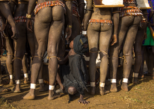 Child boy in the middle of Bodi tribe fat men legs during Kael ceremony, Omo valley, Hana Mursi, Ethiopia