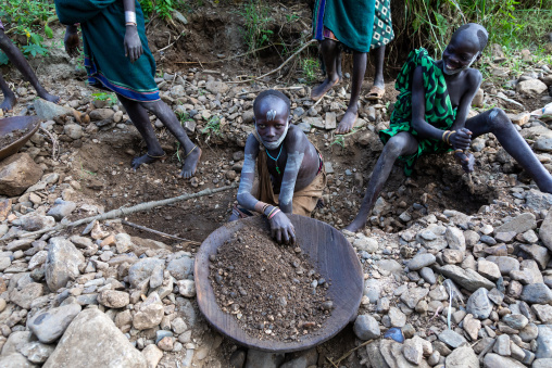 Suri tribe girls doing gold panning in a river, Omo valley, Kibish, Ethiopia