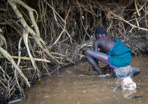 Suri tribe girls doing gold panning in a river, Omo valley, Kibish, Ethiopia