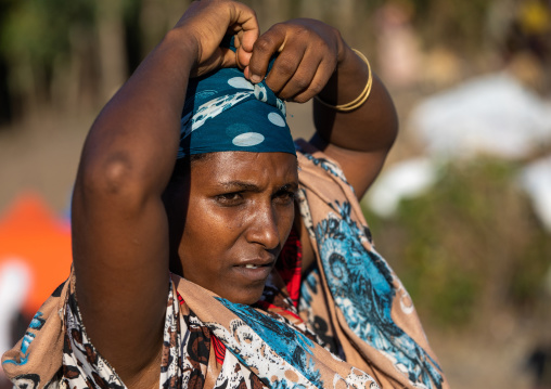 Oromo woman in a market putting her headscarf, Amhara region, Senbete, Ethiopia