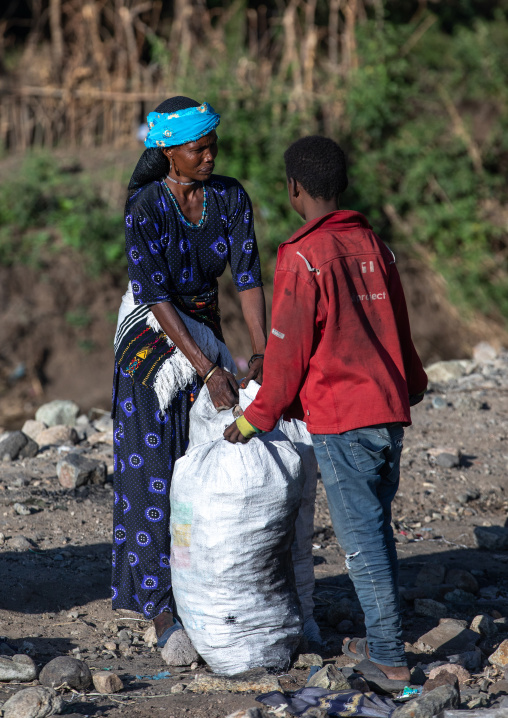 Ethiopan people packing charcoal in bags on a market, Amhara region, Senbete, Ethiopia