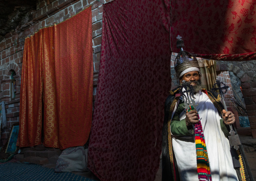 Ethiopian orthodox priest in nakuto lab rock church holding a cross, Amhara Region, Lalibela, Ethiopia