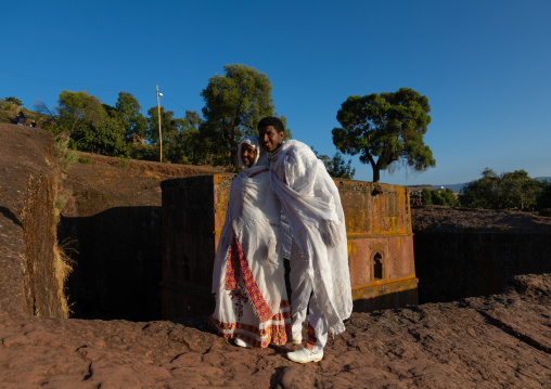 Ethiopian new wed couple pausing in front of the monolithic rock-cut church of bete giyorgis, Amhara Region, Lalibela, Ethiopia