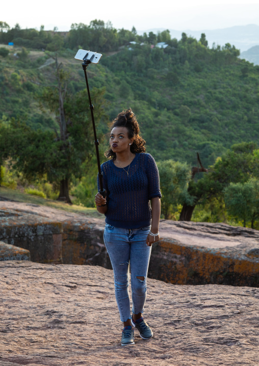 Ethiopian tourist taking a selfie in front of the monolithic rock-cut church of bete giyorgis, Amhara Region, Lalibela, Ethiopia