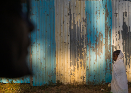 Ethiopian woman passing in front a metalic fence, Addis Ababa Region, Addis Ababa, Ethiopia