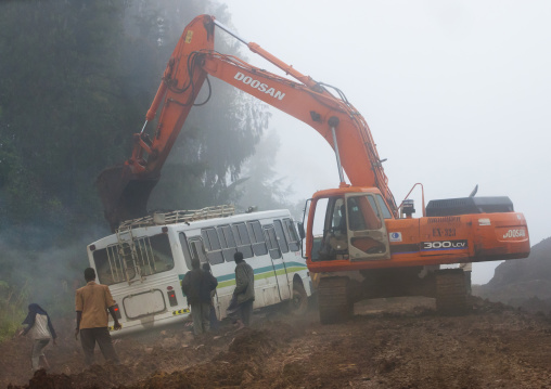 A Mechanical Digger Trying To Pull Back On Track A Bus Stuck On The Muddy Path Of A Construction Site, Hossana, Omo Valley Ethiopia