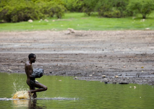 Borana Tribe Man Getting Out Of The Crater Lake Of El Sod Volcano With Volcanic Mud In The Arms, Omo Valley, Ethiopia