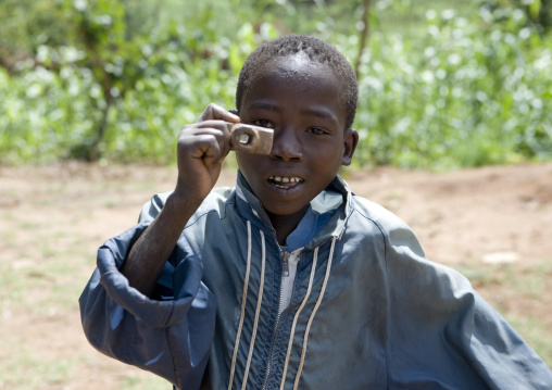 Portrait Of A Konso Tribe Boy Pretending To Take A Picture With A Fake Wooden Camera, Konso, Omo Valley, Ethiopia