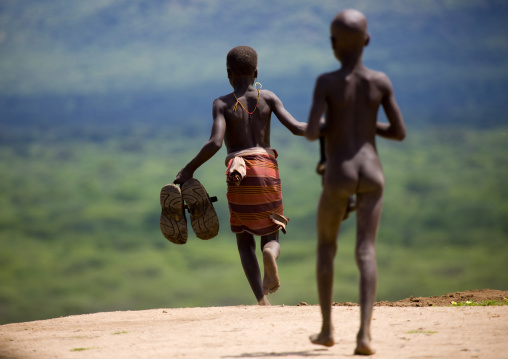 Karo Young Boys Running With Giant Shoes In Hand Ethiopia