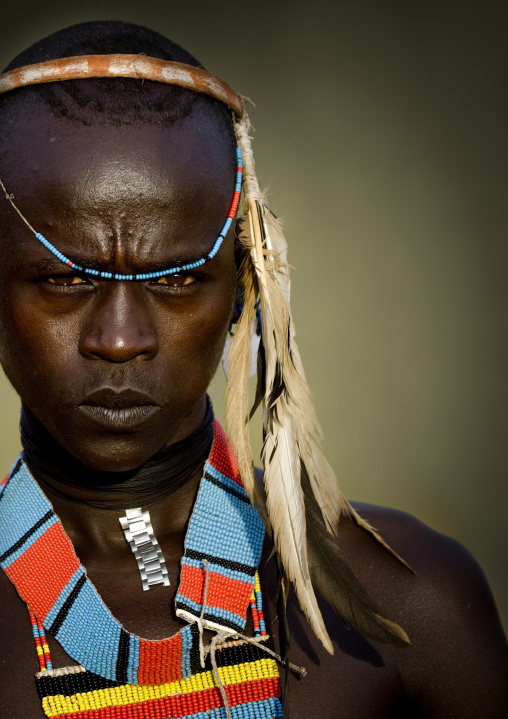 Portrait of a young tsamay whipper with feathers attached to his hairband and traditional necklace, Turmi, Ethiopia