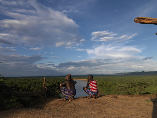 Two Karo Men Squatting While They Look At The River Down Hill Omo Valley Ethiopia