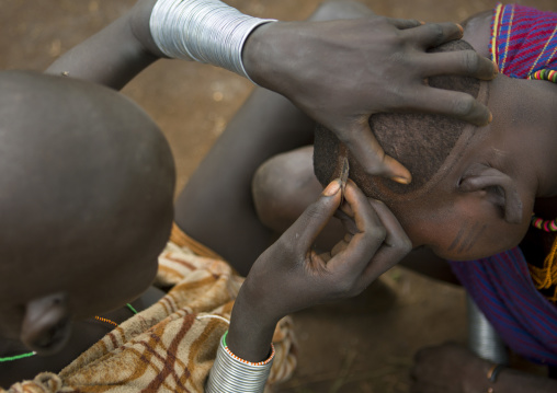 Suri tribe woman cutting hair with a blade, Kibish, Omo valley, Ethiopia