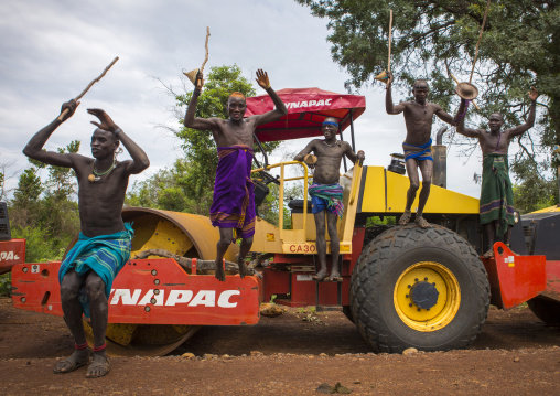 Bodi Tribe Warriors Proudly Jumping From A Bulldozer Near Hana Mursi, Omo Valley, Ethiopia