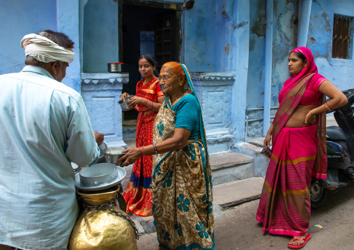 Indian man delivering fresh milk door to door with his motorbike, Rajasthan, Bundi, India