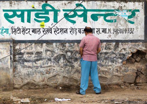 Indian man peeing outside on a wall, Rajasthan, Sawai Madhopur, India