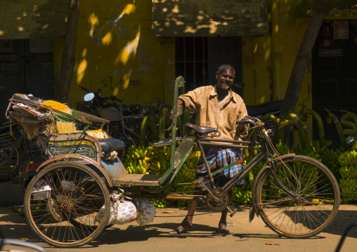 Cycle Rickshaw Driver Posing In Front Of Bunches Of Bananas In A Street Of Pondicherry, India