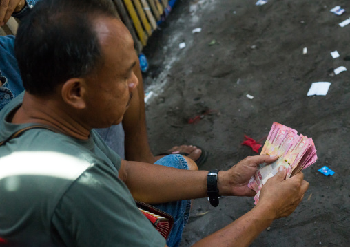 Men Taking The Money For The Bets During A Cockfigting Event