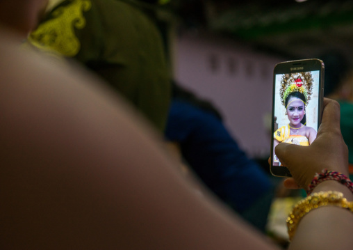 A Teenager Girl In Traditional  Costume Using Her Mobile Phone As A Mirror  Before A Tooth Filing Ceremony