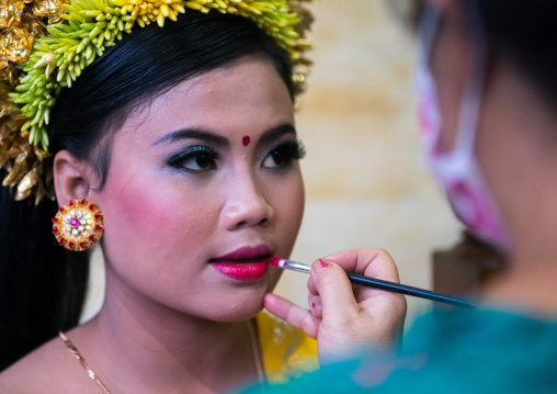 A Woman Applying Makeup To A Teenager Girl In Traditional  Costume Before A Tooth Filing Ceremony