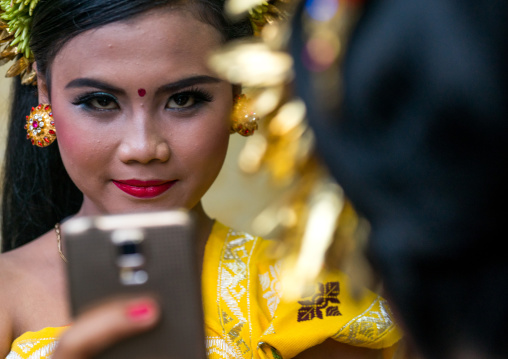 A Teenager Girl In Traditional  Costume Using Her Mobile Phone As A Mirror  Before A Tooth Filing Ceremony