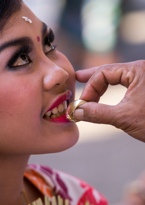 A Teenager Girl Having Her Teeth Blessed With A Ring By A Priest Before A Tooth Filing Ceremony