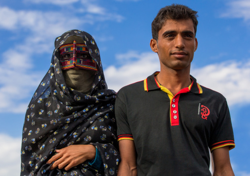 a bandari woman with her husband wearing a traditional mask called the burqa at panjshambe bazar, Hormozgan, Minab, Iran