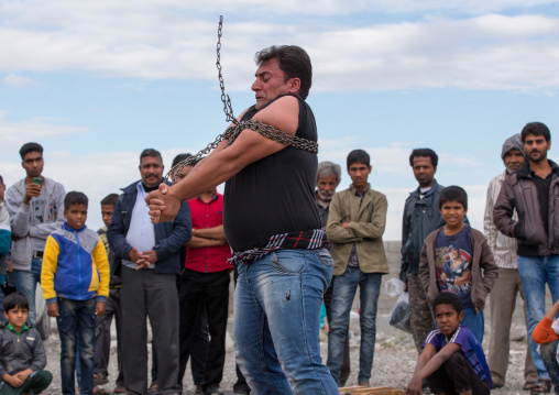 a strongman struggles to break free of chains at the panjshambe bazar thursday market, Hormozgan, Minab, Iran