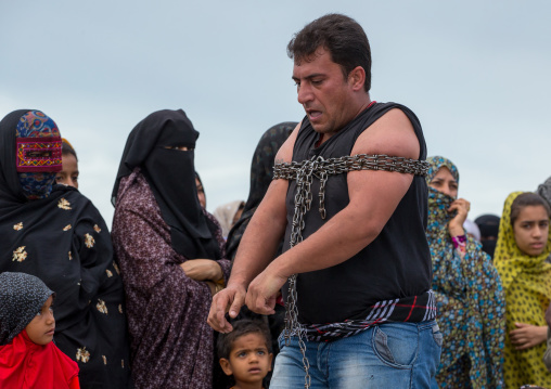 a strongman struggles to break free of chains at the panjshambe bazar thursday market, Hormozgan, Minab, Iran