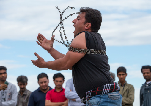 a strongman struggles to break free of chains at the panjshambe bazar thursday market, Hormozgan, Minab, Iran