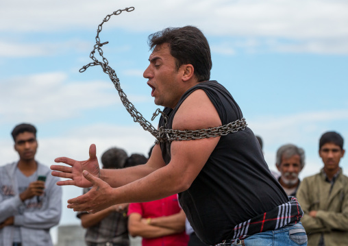 a strongman struggles to break free of chains at the panjshambe bazar thursday market, Hormozgan, Minab, Iran