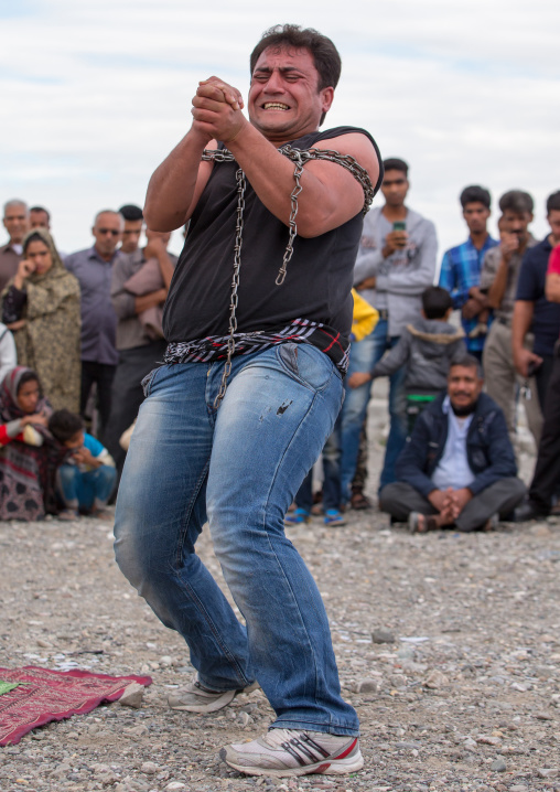 a strongman struggles to break free of chains at the panjshambe bazar thursday market, Hormozgan, Minab, Iran