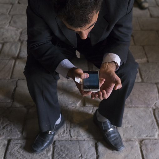 Man reading a pray on his mobile phone inside the friday mosque, Isfahan province, Isfahan, Iran