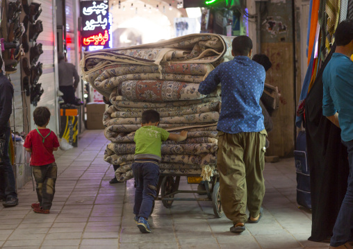 People pushing a cart full of carpets inside the bazaar, Isfahan province, Kashan, Iran