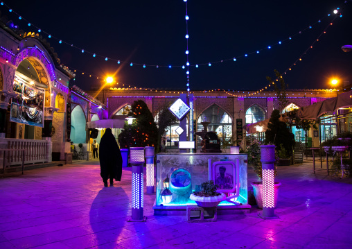 Iranian woman in chador going inside a mosque illuminated for Muharram to commemorate the martyrdom anniversary of Hussein, Isfahan Province, Isfahan, Iran