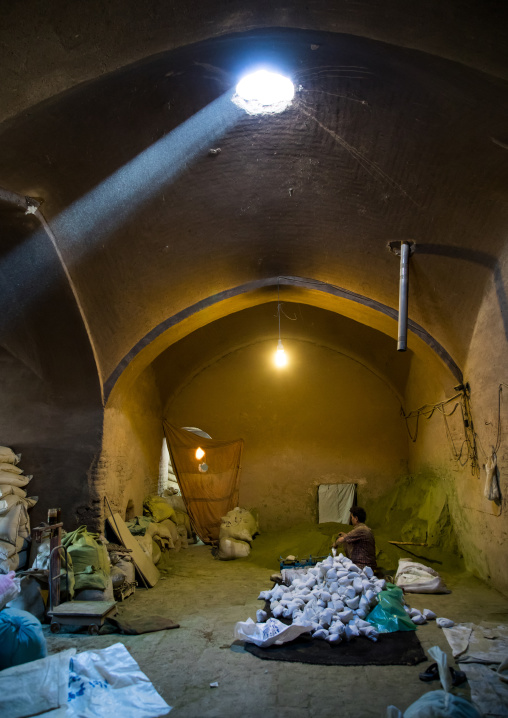 Afghani worker packing henna bags in a traditional mill, Yazd Province, Yazd, Iran