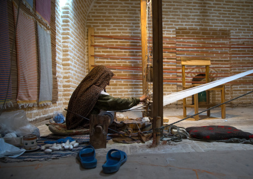 An old woman making a carpet in a caravanserai, Yazd Province, Meybod, Iran