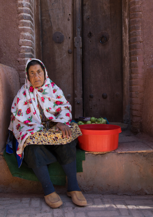 Portrait of an iranian woman wearing traditional floreal chador cooking apples, Natanz County, Abyaneh, Iran