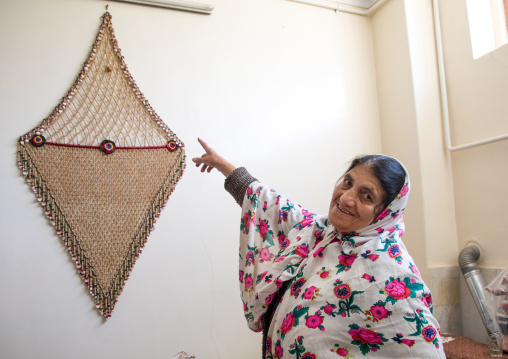 Portrait of an iranian woman wearing traditional floreal chador and showing a lucky charm, Natanz County, Abyaneh, Iran