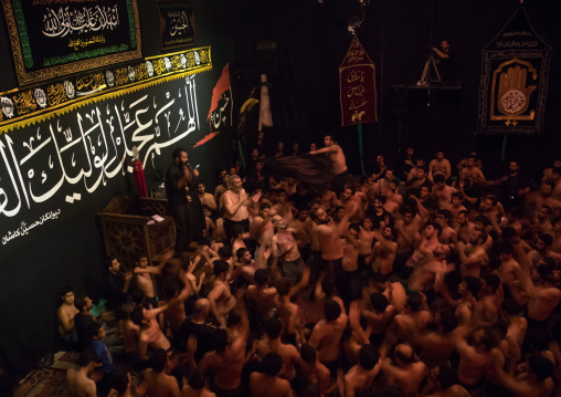 Iranian shiite muslim mourners from the mad of Hussein community chanting and self-flagellating during Muharram in their hosseinieh, Isfahan Province, Kashan, Iran