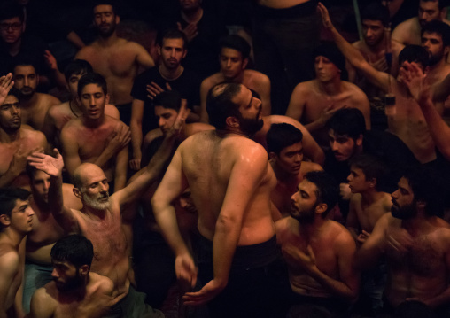 Iranian shiite muslim mourners from the mad of Hussein community chanting and self-flagellating during Muharram in their hosseinieh, Isfahan Province, Kashan, Iran