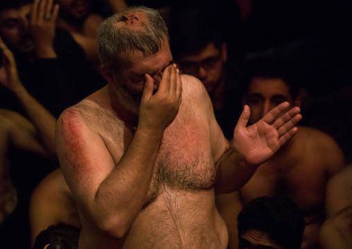 Portrait of iranian shiite muslim mourner from the mad of Hussein community chanting and self-flagellating during Muharram in a Hosseinieh, Isfahan Province, Kashan, Iran