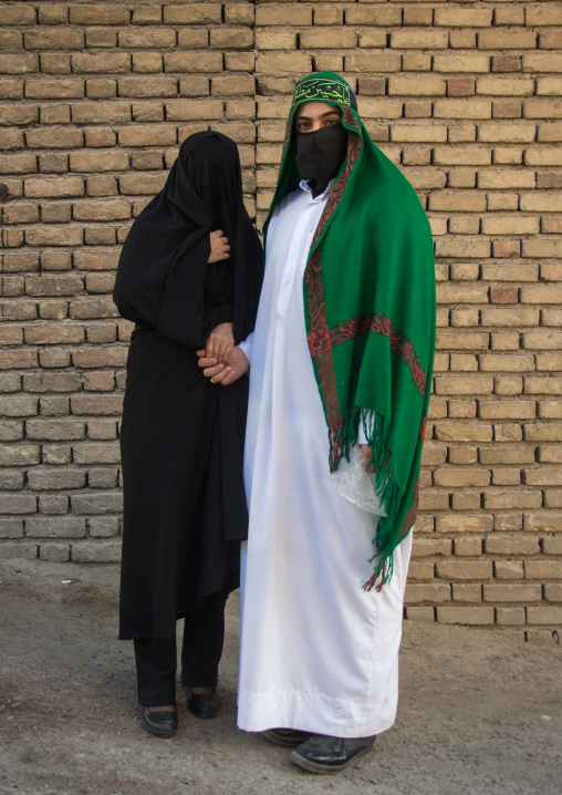 Portrait of iranian shiite muslim couple with their faces hidden by a veil mourning Imam Hussein on Tasua during the Chehel Manbar ceremony one day before Ashura, Lorestan Province, Khorramab