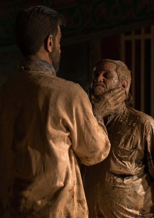 Iranian shiite muslim man rubbes mud on the face of his friend during the Kharrah Mali ritual to mark the Ashura ceremony, Lorestan Province, Khorramabad, Iran