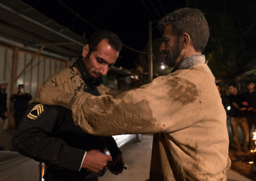 Iranian shiite muslim man rubbes mud on the face of a Policeman during the Kharrah Mali ritual to mark the Ashura ceremony, Lorestan Province, Khorramabad, Iran