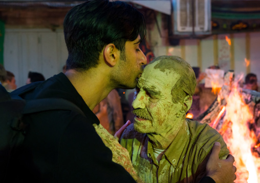 Iranian shiite muslim man kissing an old man  who rubbed mud on his body during the Kharrah Mali ritual to mark the Ashura ceremony, Lorestan Province, Khorramabad, Iran